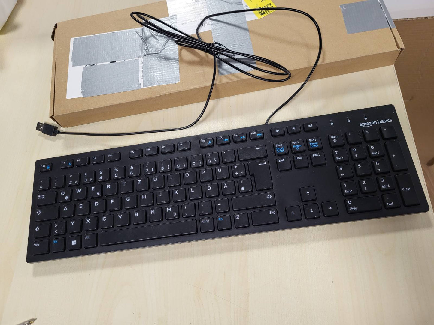 269186 - AMAZON BASICS Tastierë e sheshtë me kabllo USB, e zezë mat, paraqitje gjermane.