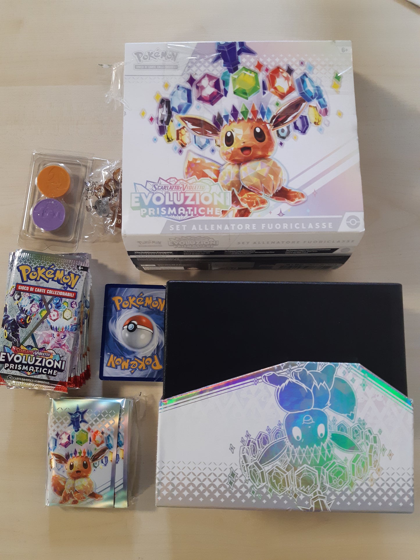 58383 - Pokémon TCG: KUTI E TRAJNERIT ELIT - Evolucione Prizmatike nga bordoja e kuqe dhe e vjollcë (1 kartë promocionale me art të plotë, 9 paketa përforcuese dhe aksesorë premium), në gjuhën italiane