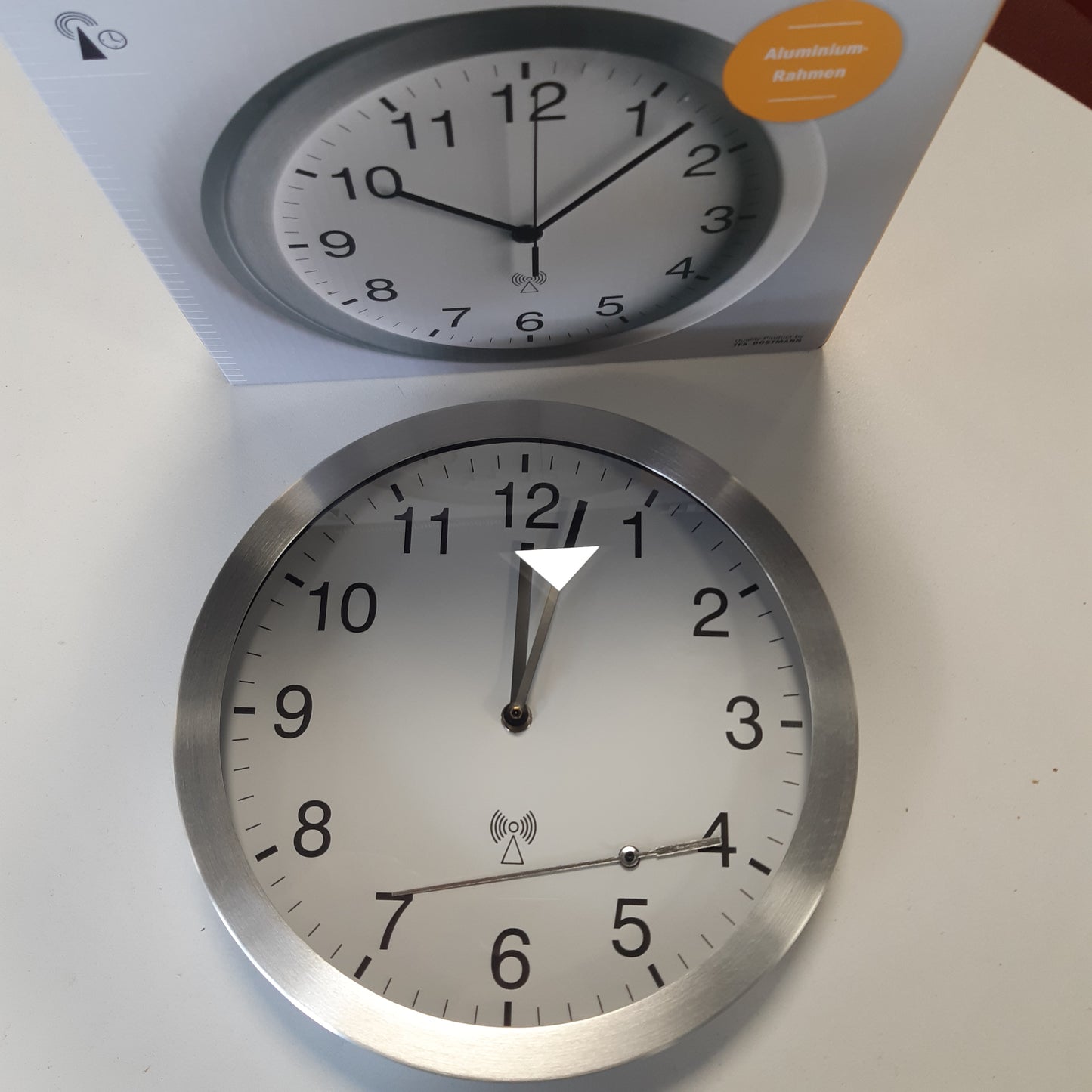 261755 - TFA DOSTMANN Orë muri analoge me radio-kontroll, 98.1091, kornizë alumini, diametër 25 cm, e bardhë-argjendtë