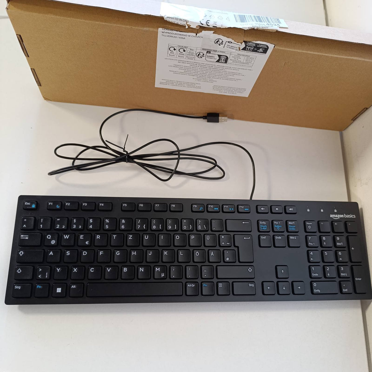 320515 - Tastierë AMAZON BASICS me paraqitje gjermane, e sheshtë, me kabllo USB, e zezë mat