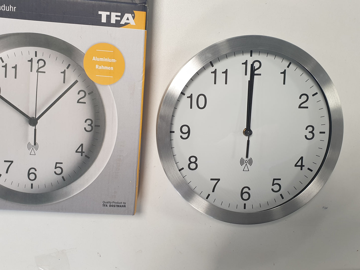 222801 - TFA DOSTMANN Orë muri analoge me radio-kontroll, 98.1091, me kornizë alumini, diametër 25 cm, e bardhë-argjendtë