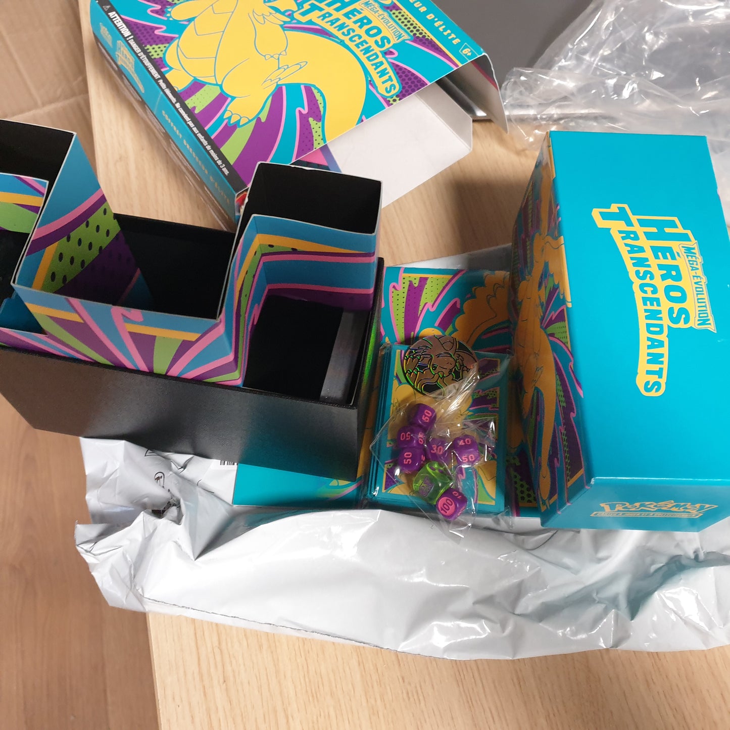 141773 - Pokémon: Mega Evolution Elite Trainer Set – Transcendent Heroes, përfshin 1 kartë promo të ilustruar, 9 pako booster dhe aksesorë premium për lojë.
