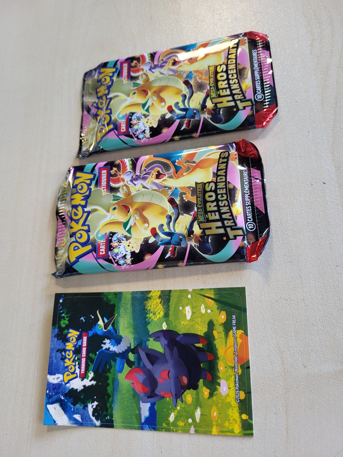 141562 - Pokémon: Mega Evolution Mini Box – Transcendent Heroes – Zorua dhe Nigosier (1 faqe stickers, 1 kartë arti dhe 2 paketa përforcuese).