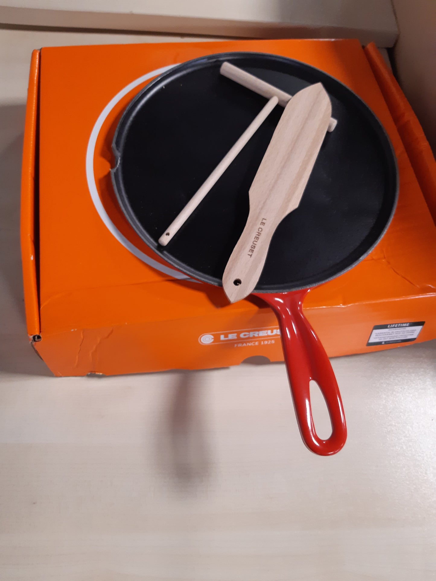 177046 - LE CREUSET Tigan prej Gize të Emaluar për Krepa me Dorezë Hekuri dhe Shpatullë Druri, 27 cm, 2.17 kg, Ngjyra Qershi, Modeli 20136270600460